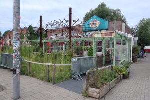 Terras van horecagelegenheid Pizza Territory aan het Gedempt Hamerkanaal in Amsterdam, omgeven door planten en decoratieve verlichting.
